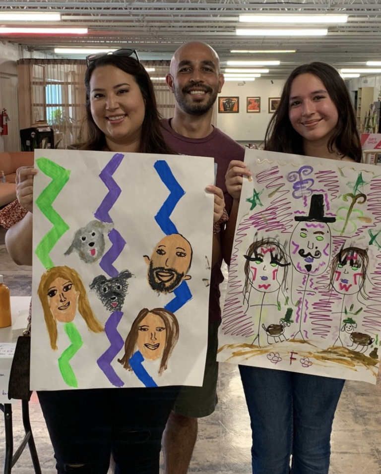 This is a photo of a family holding their family portraits during a SAY Sí Summer Saturday session.